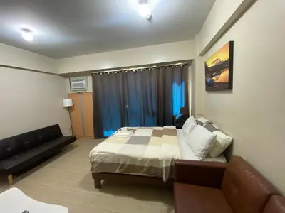 a bedroom with a bed and a couch in it at two palm tree villas condotel by kath in Manila