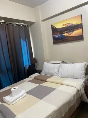 a bedroom with a large bed with blue curtains at two palm tree villas condotel by kath in Manila
