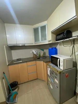 a small kitchen with a microwave on top of a refrigerator at two palm tree villas condotel by kath in Manila