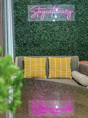 a couch with two pillows in front of a green wall at Azure Urban Resort Residences - Staycationary Miami 1710 in Manila