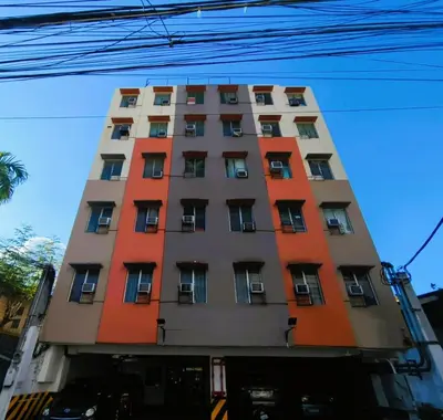 a tall orange and gray building with windows at BGC Suites Uptown in Makati