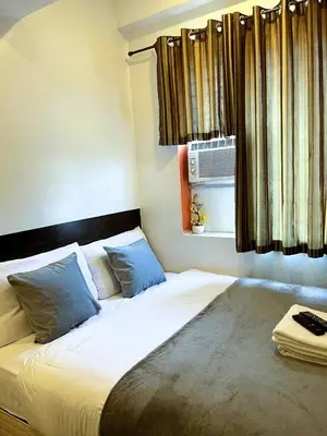 a bed with two pillows and a window at BGC Suites Uptown in Makati