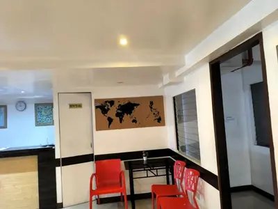 a room with red chairs and a table and a painting at BGC Suites Uptown in Makati