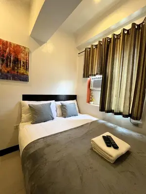a bedroom with a large bed with a towel on it at BGC Suites Uptown in Makati
