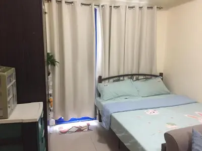 a bedroom with two beds and a window with curtains at Arcilla stay cation in Manila