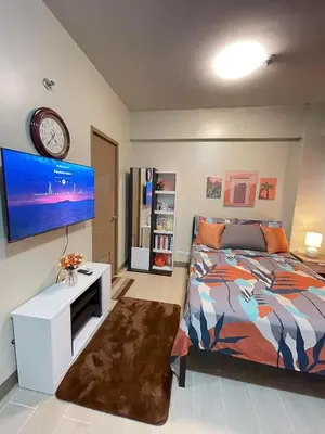 a bedroom with a bed and a flat screen tv at Airport NAIA T3 Condotel in Manila
