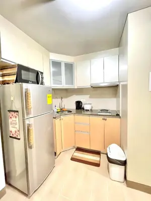 a kitchen with a stainless steel refrigerator and white cabinets at Airport NAIA T3 Condotel in Manila