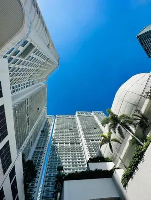 a tall building with palm trees in front of it at MADR Excellence at Novotel Manila Hotel Residence Acqua in Manila
