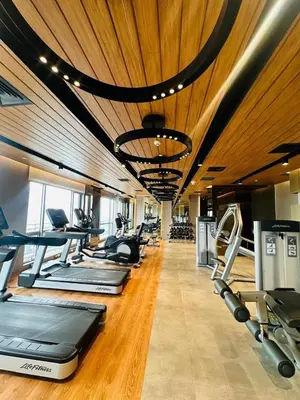 a gym with a row of treadms and cardio machines at MADR Excellence at Novotel Manila Hotel Residence Acqua in Manila