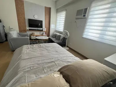 a bedroom with a large bed and a living room at Aras Solace Place in Trece Martires