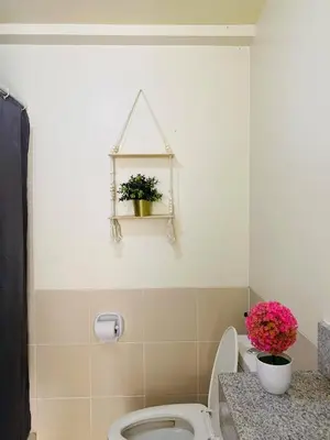 a bathroom with a toilet and flowers on a counter at timoncondotel city view in Manila