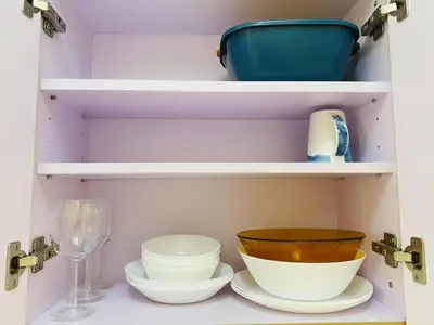 a cupboard with plates and bowls and a wine glass at timoncondotel city view in Manila