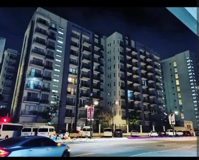 a car driving down a street in front of tall buildings at One Palm Tree Villas Near NAIA 3 in Manila