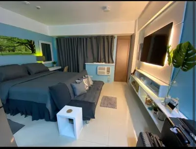 a bedroom with a blue bed and a couch at One Palm Tree Villas Near NAIA 3 in Manila
