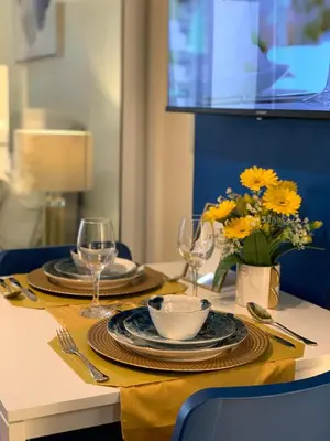 a table with plates and glasses and a vase of flowers at CASA ROYALE Affordable Condo Near BGC Ortigas Center CBD in Manila