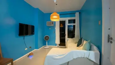a blue room with a white bed and a tv at The Radiance Manila Bay by Mary in Manila
