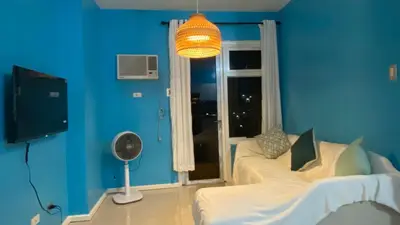 a blue room with two beds and a window at The Radiance Manila Bay by Mary in Manila