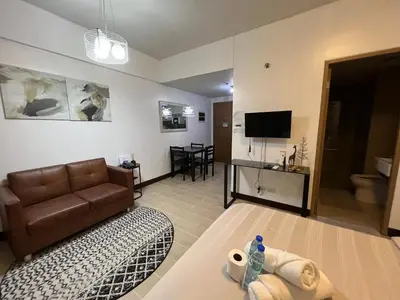 a living room with a couch and a television at Two Palm Tree Villas by Trisha in Manila