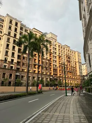 a large building with palm trees in front of a street at Two Palm Tree Villas by Trisha in Manila
