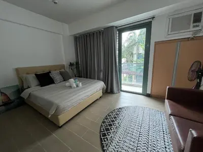 a bedroom with a bed and a large window at Two Palm Tree Villas by Trisha in Manila