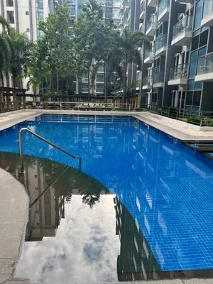 a large blue swimming pool with buildings in the background at Two Palm Tree Villas by Trisha in Manila