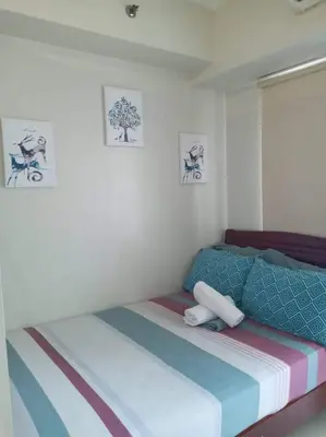 a bed in a room with two pictures on the wall at Bj's Staycation Manila - SEA Residences SM MOA in Manila