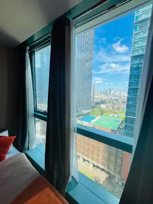 a bedroom with a window with a view of a city at BGC One Uptown Residences in Manila