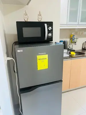 a microwave on top of a refrigerator in a kitchen at BGC One Uptown Residences in Manila