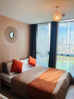 a bedroom with a bed with orange pillows and a window at BGC One Uptown Residences in Manila