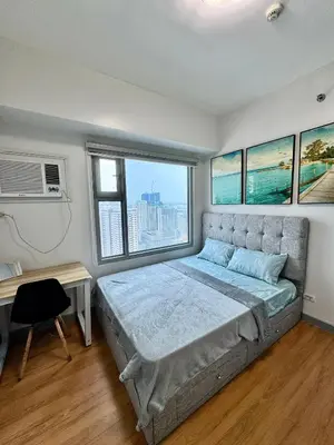 a bedroom with a bed and a desk and windows at Cozy 1BR Condo in Manila Near US Embassy and Robinsons Place Manila in Manila