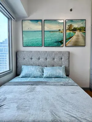 a bedroom with four pictures hanging above a bed at Cozy 1BR Condo in Manila Near US Embassy and Robinsons Place Manila in Manila