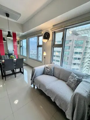a living room with a couch in a room with windows at Cozy 1BR Condo in Manila Near US Embassy and Robinsons Place Manila in Manila