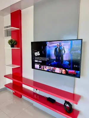 a flat screen tv on a red entertainment center at Cozy 1BR Condo in Manila Near US Embassy and Robinsons Place Manila in Manila