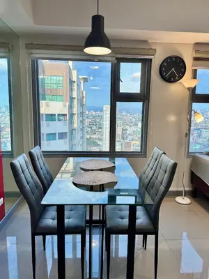 a dining room with a table and chairs and a clock at Cozy 1BR Condo in Manila Near US Embassy and Robinsons Place Manila in Manila