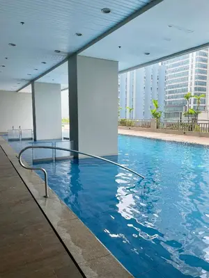 a swimming pool with blue water in a building at Cozy 1BR Condo in Manila Near US Embassy and Robinsons Place Manila in Manila