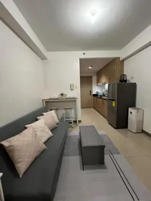 a living room with a black couch and a kitchen at My Serenity Suite in Manila
