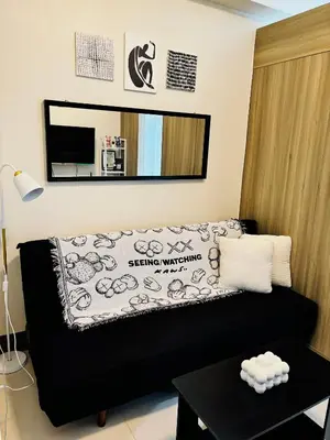 a living room with a black couch and a mirror at Serenitude Staycation by Khaila - Fame Residences in Manila