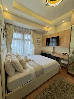 a bedroom with a bed with a desk and a television at Manila Bay Suite in Manila