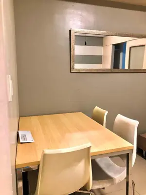 a dining room table with chairs and a mirror at Cosy Light Residences Unit Staycation in Manila