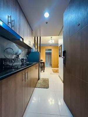 a kitchen with wooden cabinets and a hallway at M&B Staycation in Manila
