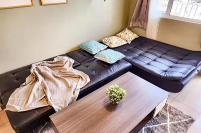 a living room with a black leather couch and a table at Lush 2br 98sqm MOA 200mbps Netflix XBOX Printer in Manila