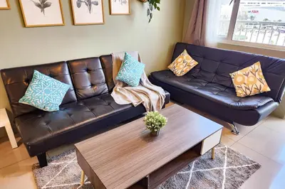 a living room with a leather couch and a coffee table at Lush 2br 98sqm MOA 200mbps Netflix XBOX Printer in Manila