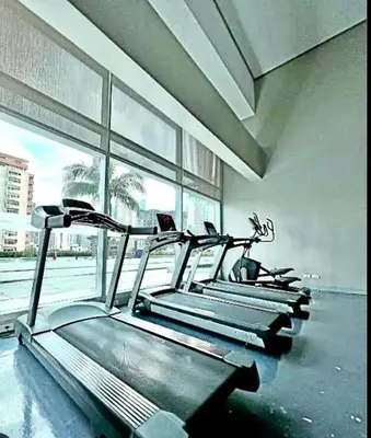 a row of cardio machines in a gym with a window at The Beacon Tower in Manila