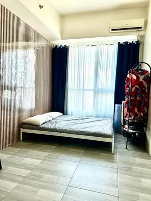 a bedroom with a bed and a window with blue curtains at The Beacon Tower in Manila