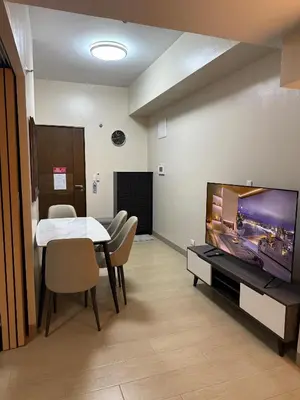a dining room with a table and a large screen tv at Superior Studio Eastwood Global Plaza Luxury Residence in Manila