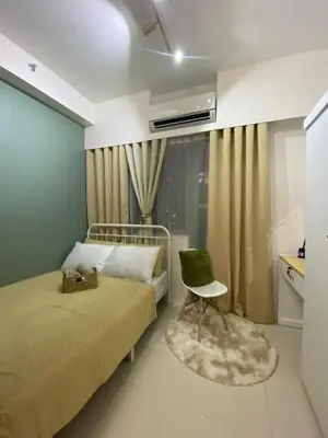 a bedroom with a bed and a chair and a window at Fame residences in Manila