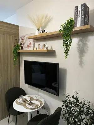 a living room with a table and a tv on a wall at Fame residences in Manila