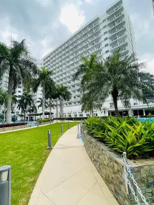a large building with palm trees in front of it at Shell Residences with MOA View near NAIA - Aiza's Place in Manila