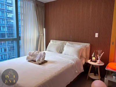 a bedroom with a large bed with a large window at Cozy & Aesthetic 1 BR in BGC in Manila