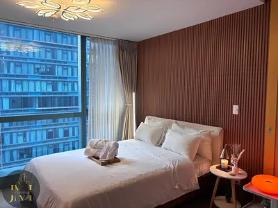 a bedroom with a large bed and a large window at Cozy & Aesthetic 1 BR in BGC in Manila